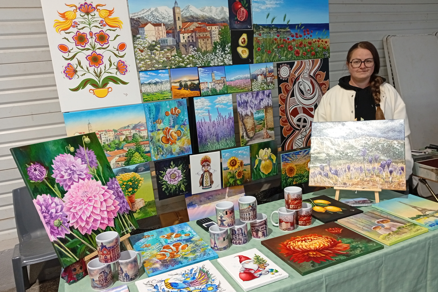 Paintings, cups, and works by Anna Mamchur at the Christmas market in Saint-Laurent-de-Cerdans